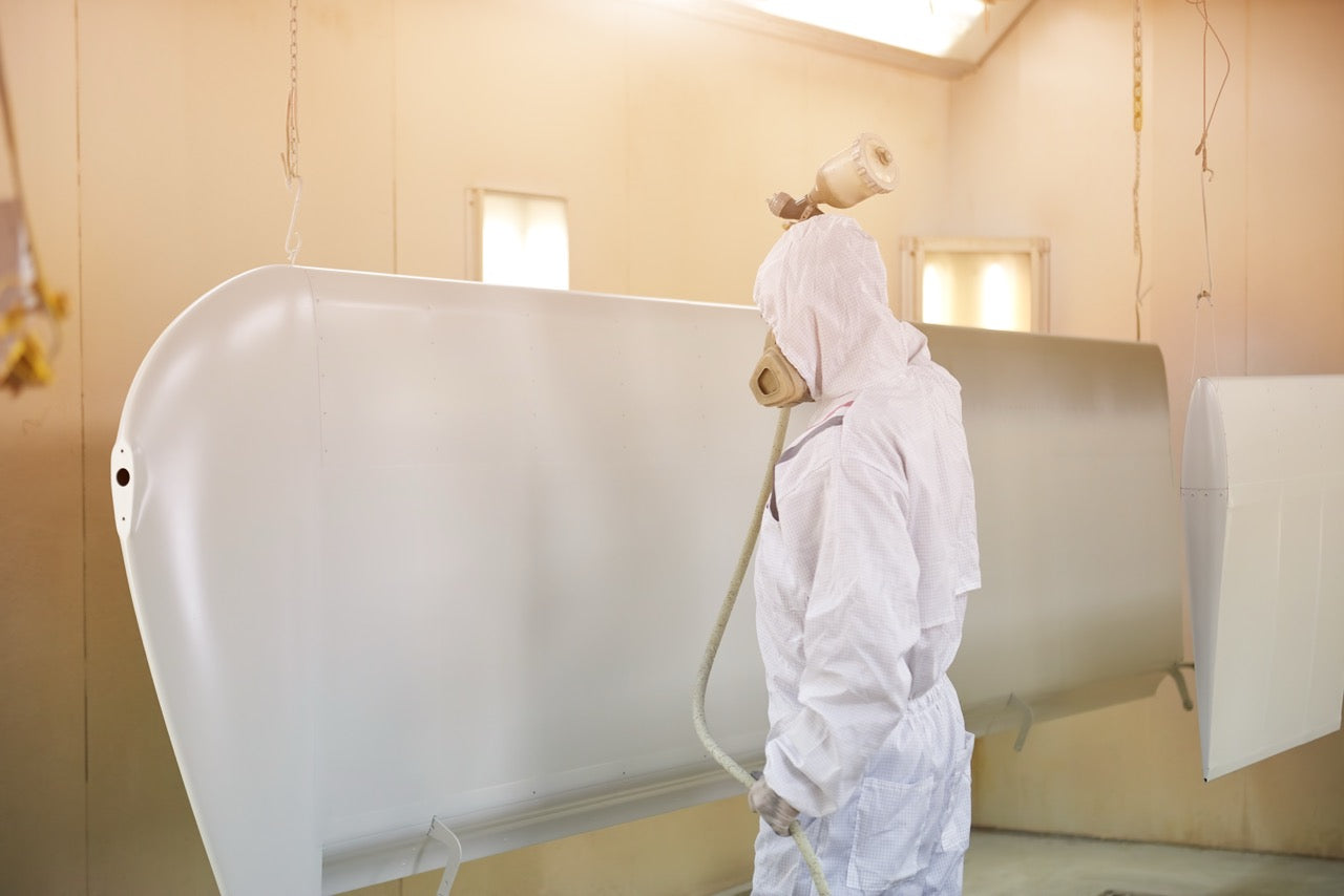 An airplane wing being sprayed by a Fuji sprayer.